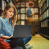Young student in library using a laptop.