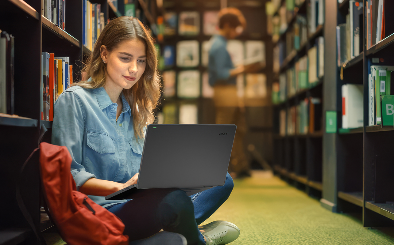 Young student in library using a laptop.