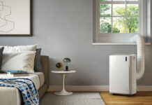 An air conditioner by a window in a bedroom.