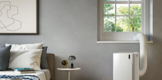 An air conditioner by a window in a bedroom.