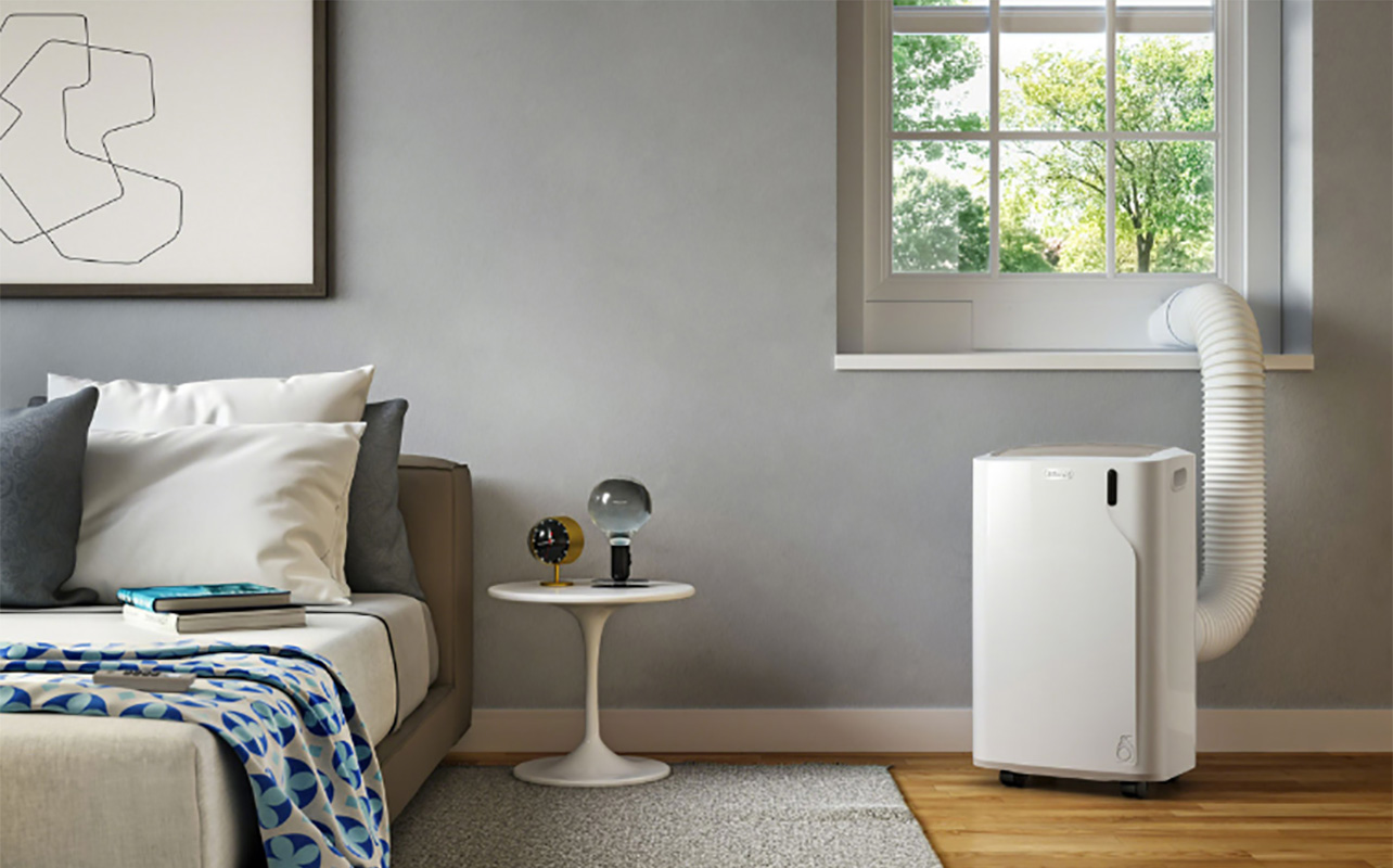 An air conditioner by a window in a bedroom.