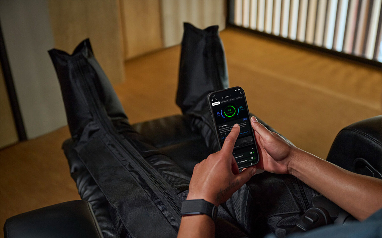 A man sitting down looking at the Amazfit app while wearing the Amazfit Tracker.