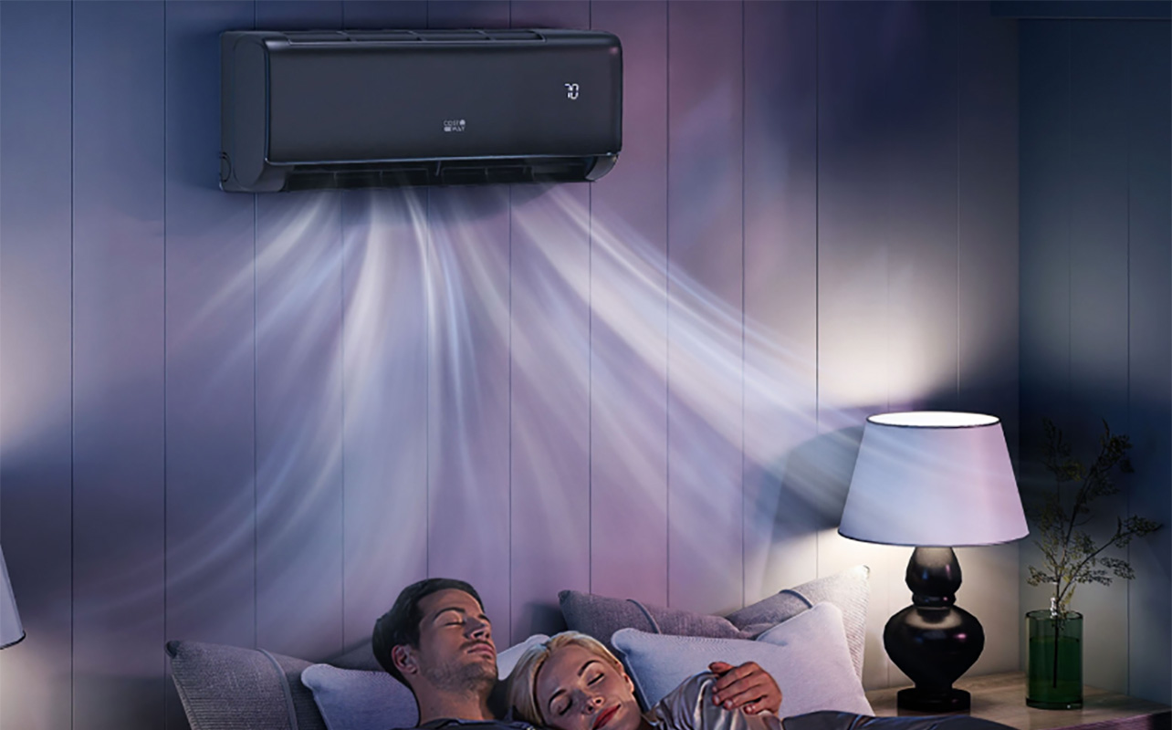 Two people sleeping in bed with a Costway mini split air conditioner above the bed.