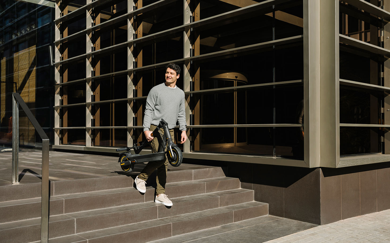 A person carries their e-scooter by hand