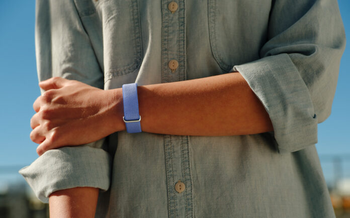 What is a screenless fitness tracker? A person's arm across their body while wearing the Fitbit Air.