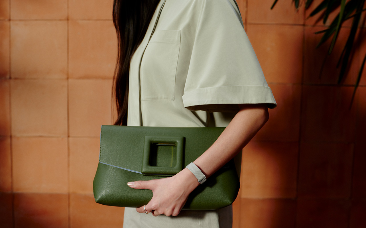 A woman carrying a green clutch while wearing the Fitbit Air.