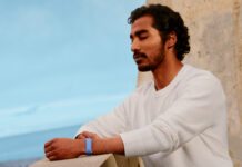 A man standing on a balcony with his eyes closed wearing the Fitbit Air.