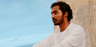 A man standing on a balcony with his eyes closed wearing the Fitbit Air.