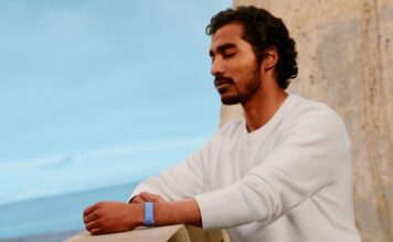 A man standing on a balcony with his eyes closed wearing the Fitbit Air.