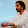 A man standing on a balcony with his eyes closed wearing the Fitbit Air.