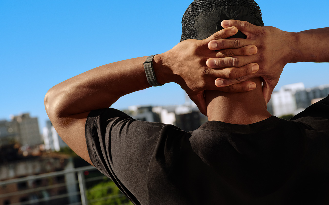 A man stretching his arms behind his head while wearing the Fitbit Air. 