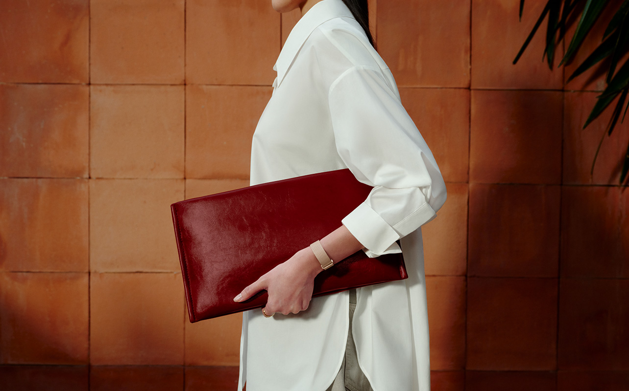 A woman walking holding a clutch bag while wearing the Fitbit Air.