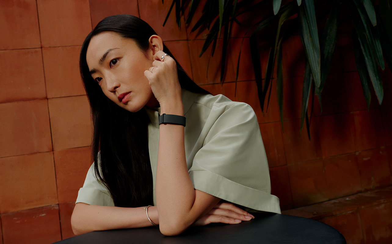 A woman sitting while wearing the Fitbit Air.