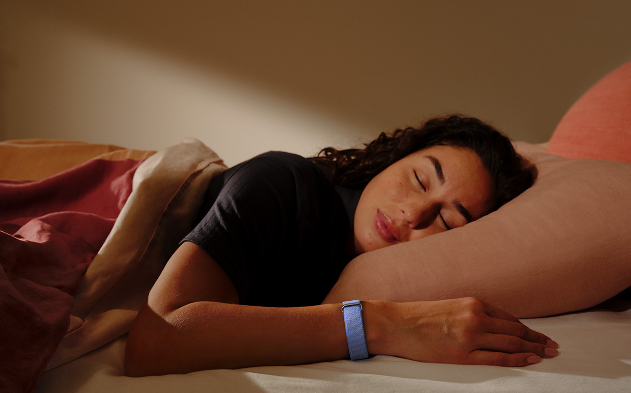 A woman sleeping while wearing the Fitbit Air.