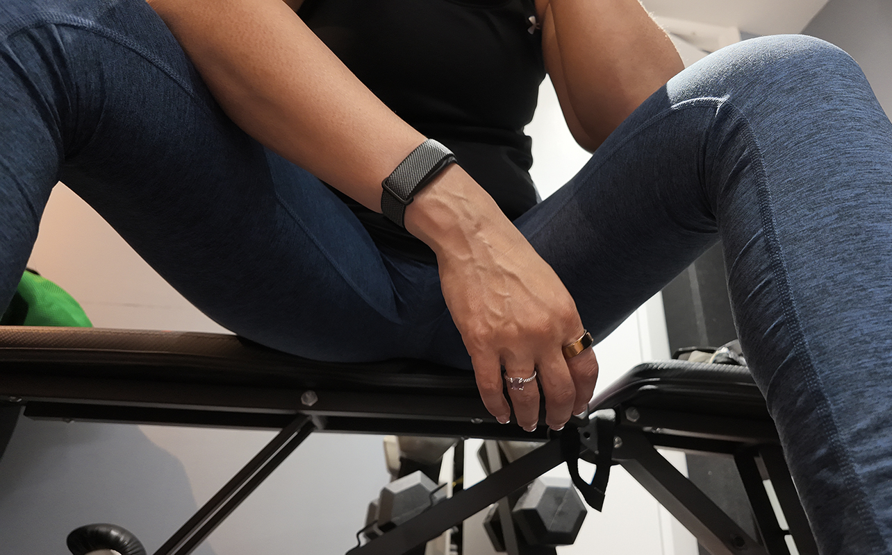 A woman sitting on a workout bench wearing the Fitbit Air.