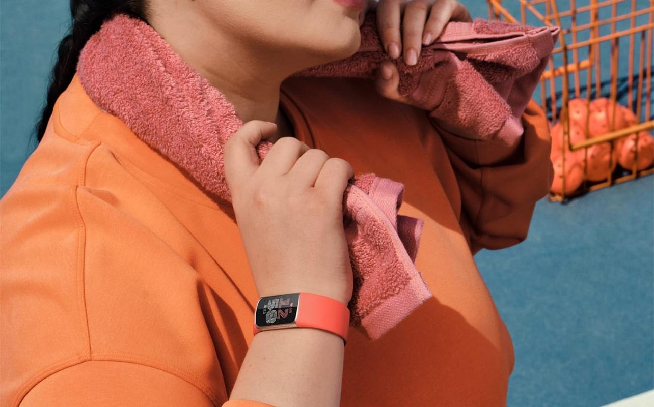 A woman holding a towel around her neck while wearing the Fitbit Charge 6.