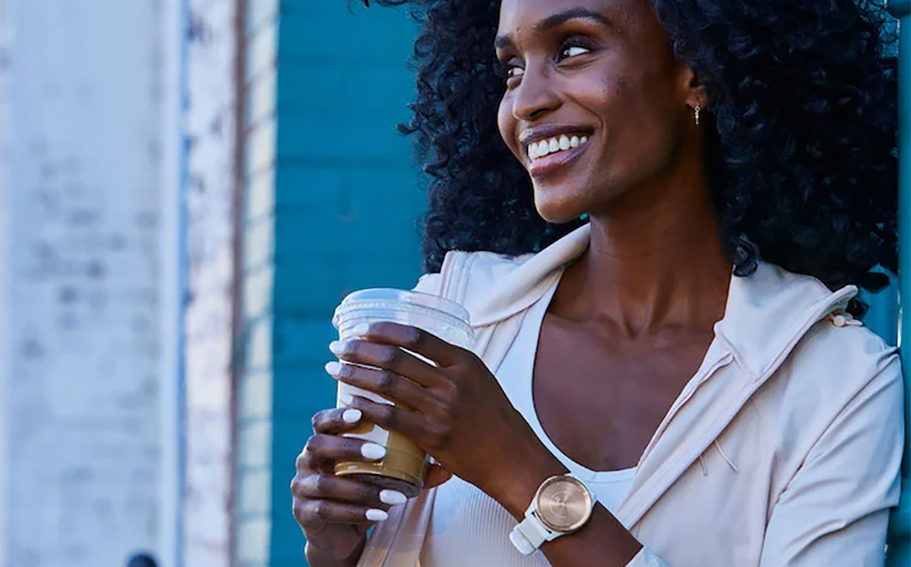 Une femme tenant une tasse de café et portant la vivomove Trend de Garmin. 
