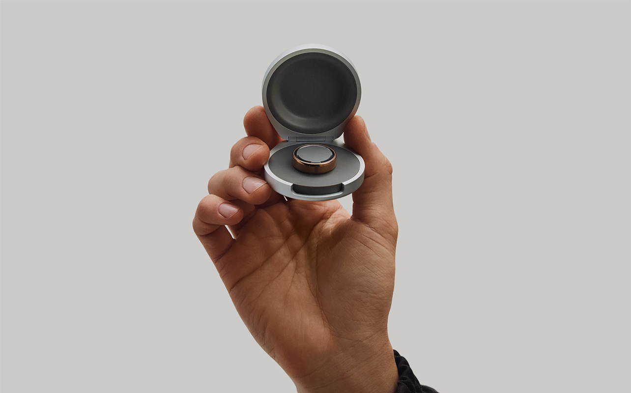 A hand holding the Oura Ring charging case.