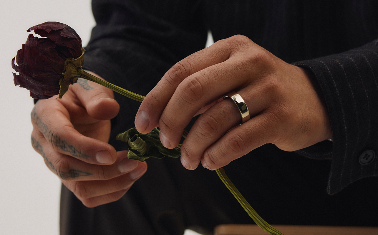 A man holding a rose and wearing the Oura Ring 5 smart ring.