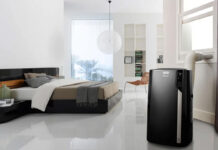 A black portable air conditioner in a bedroom.