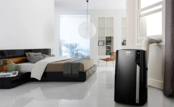 A black portable air conditioner in a bedroom.