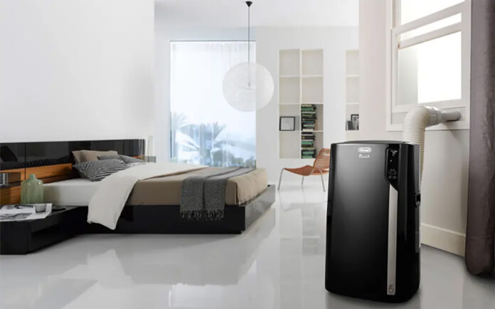 Best portable air conditioners for summer 2026 A black portable air conditioner in a bedroom.
