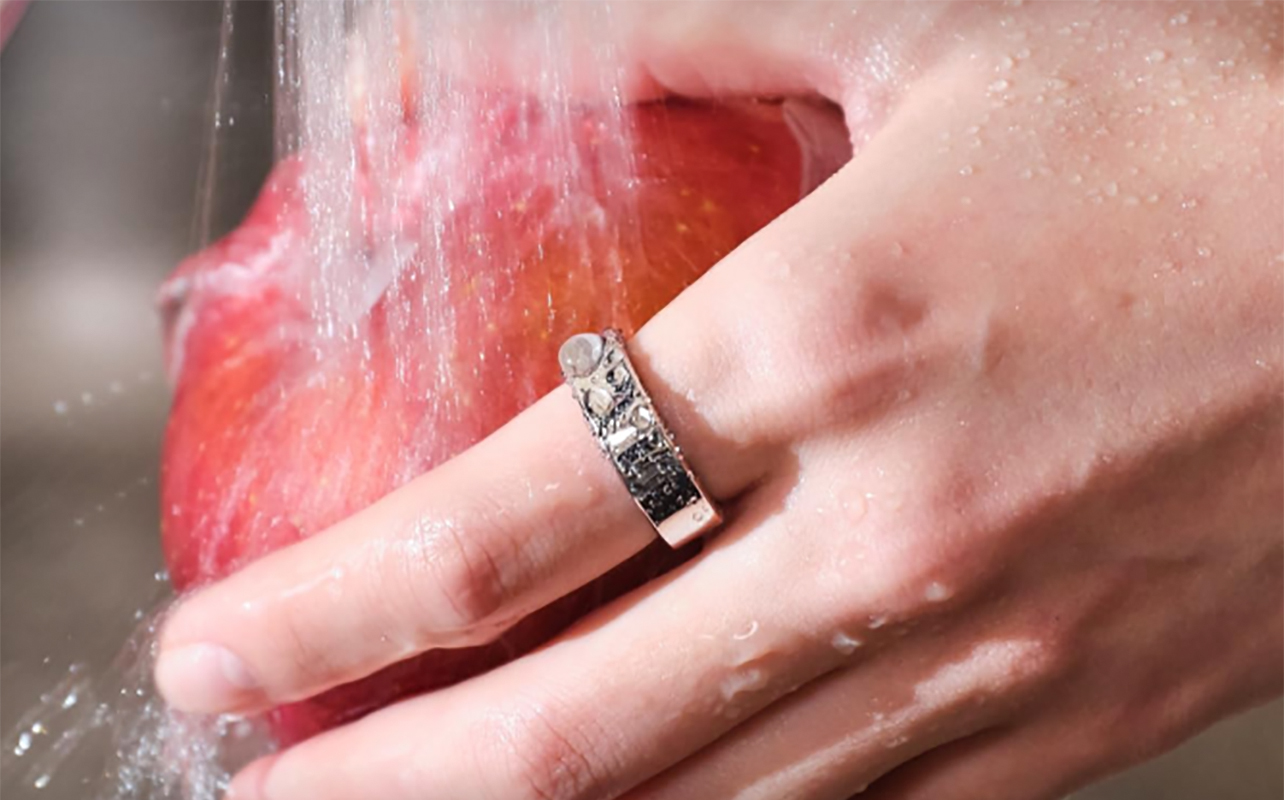 A hand washing an apple while wearing the Ringconn Gen 2