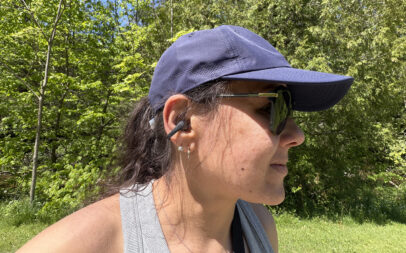 A woman wearing the Shokz OpenDots 2 earbuds outside.