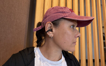 A woman wearing the Shokz OpenDots 2 earbuds in a coffee shop.