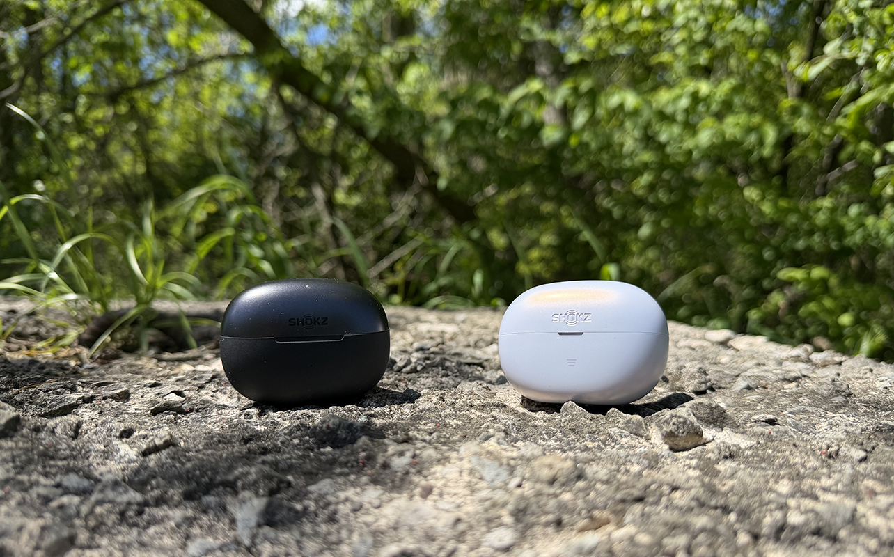 Shokz OpenDots 2 and OpenDots Ar in their closed cases outside on a rock.