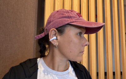 A woman wearing the Shokz OpenDots Air earbuds in a coffee shop.