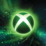 Glowing XBOX logo surrounded by green and blue particle effects on a dark background.