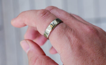 Oura Ring 5 in gold on index finger.
