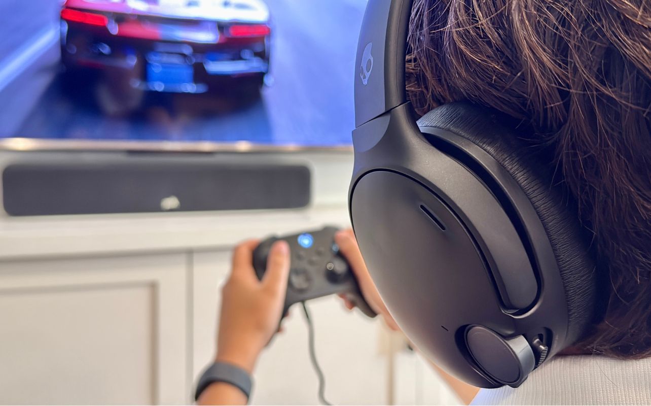 A person plays Forza Horizon 6 while enjoying the audio from the Skullcandy Crusher 1080 ANC headset.