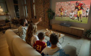 A family watching TV in the living room with the Epson Lifestudio Grand Plus projector.