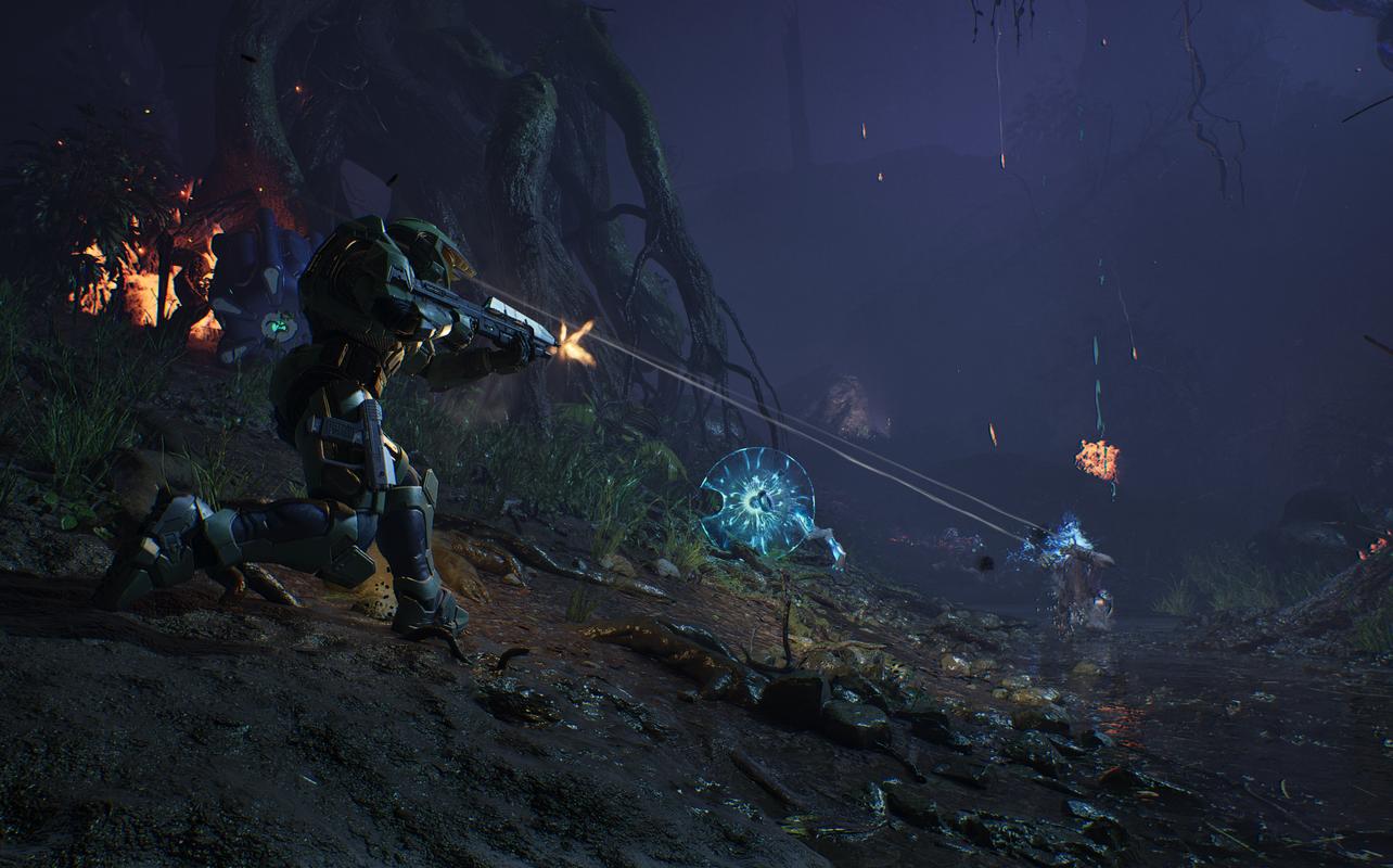 Master Chief fires at Covenant forces in a dark outdoor area in Halo: Campaign Evolved.