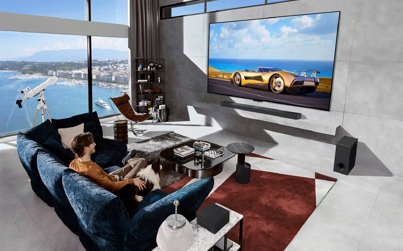 A man sitting in a room by a large window watchig an LG AI TV.