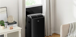 A black Midea portable air conditioner mounted at a window.