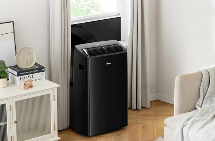 A black Midea portable air conditioner mounted at a window.