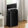 A black Midea portable air conditioner mounted at a window.