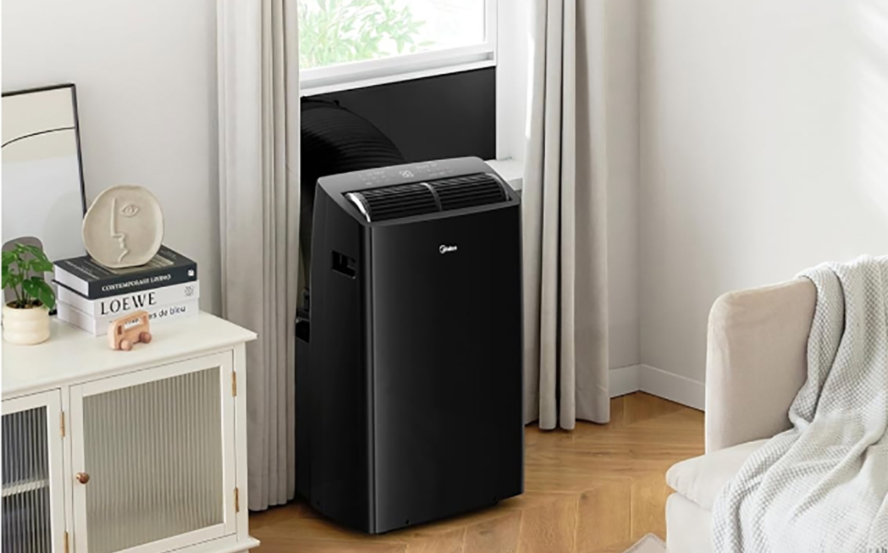 A black Midea portable air conditioner mounted at a window.