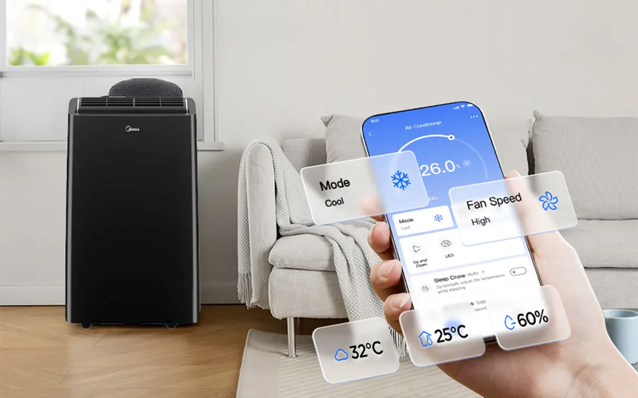 A hand holding a phone with the Midea app in front of a Midea portable air conditioner by a window.