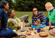 A group of young people having a picnic with he Xgimi Vibe One portable projector in the middle.