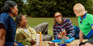 A group of young people having a picnic with he Xgimi Vibe One portable projector in the middle.