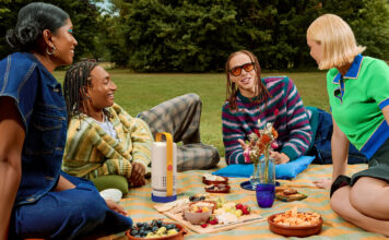 Create the ultimate backyard theatre with these outdoor projectors A group of young people having a picnic with he Xgimi Vibe One portable projector in the middle.