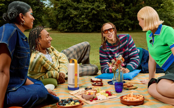A group of young people having a picnic with he Xgimi Vibe One portable projector in the middle.