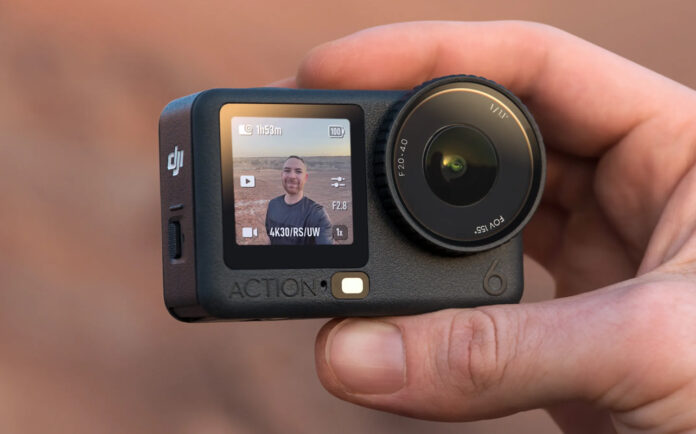Man holding DJI Osmo Action 6 at himself outdoors.