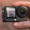 Man holding DJI Osmo Action 6 at himself outdoors.