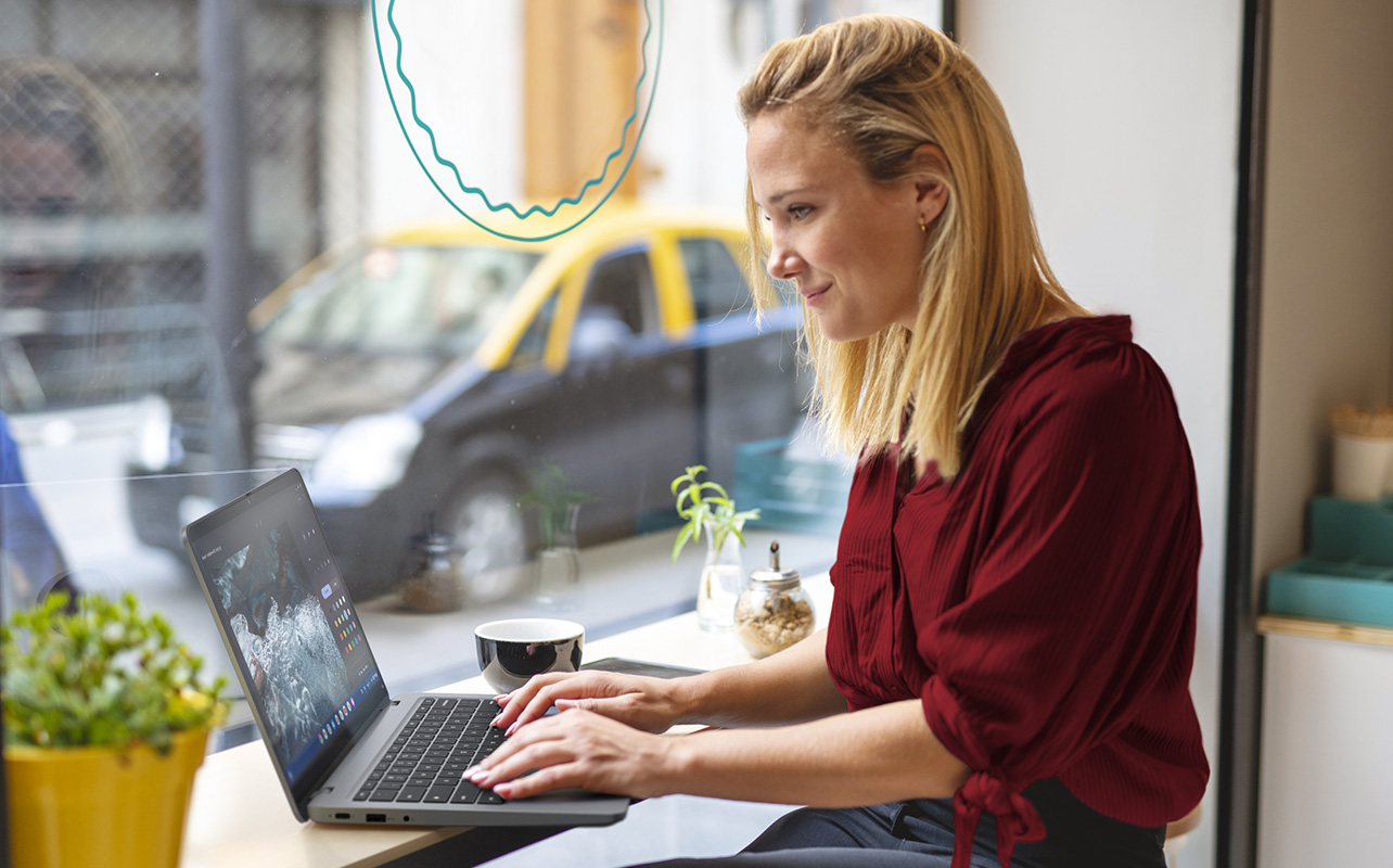 Woman working on laptop by cafe window