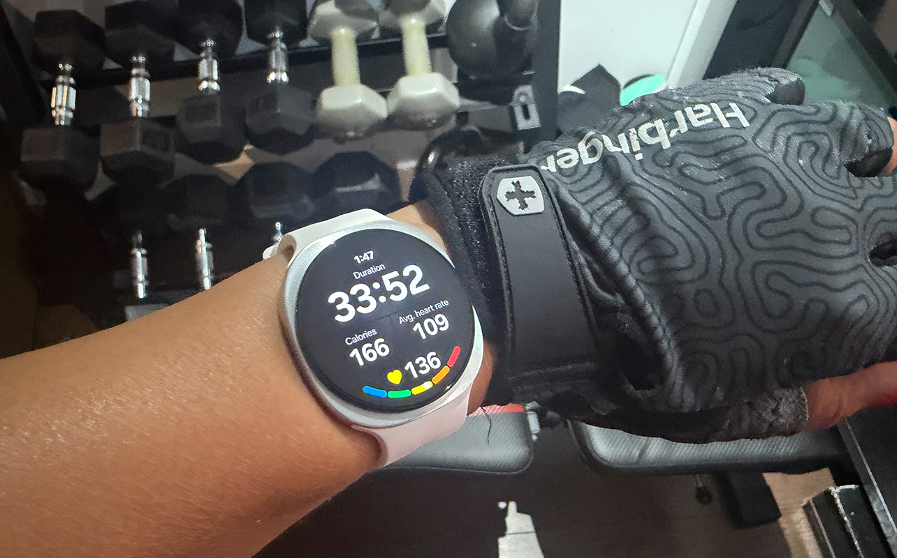 A hand wearing the Samsung Galaxy Watch 9 showing a workout in progress in front of weights.